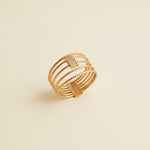 Gold ring on a cylindrical beige object against a light gray background