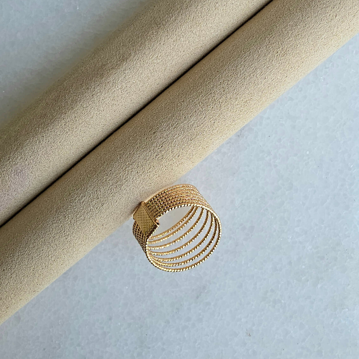 Gold ring on a textured beige surface
