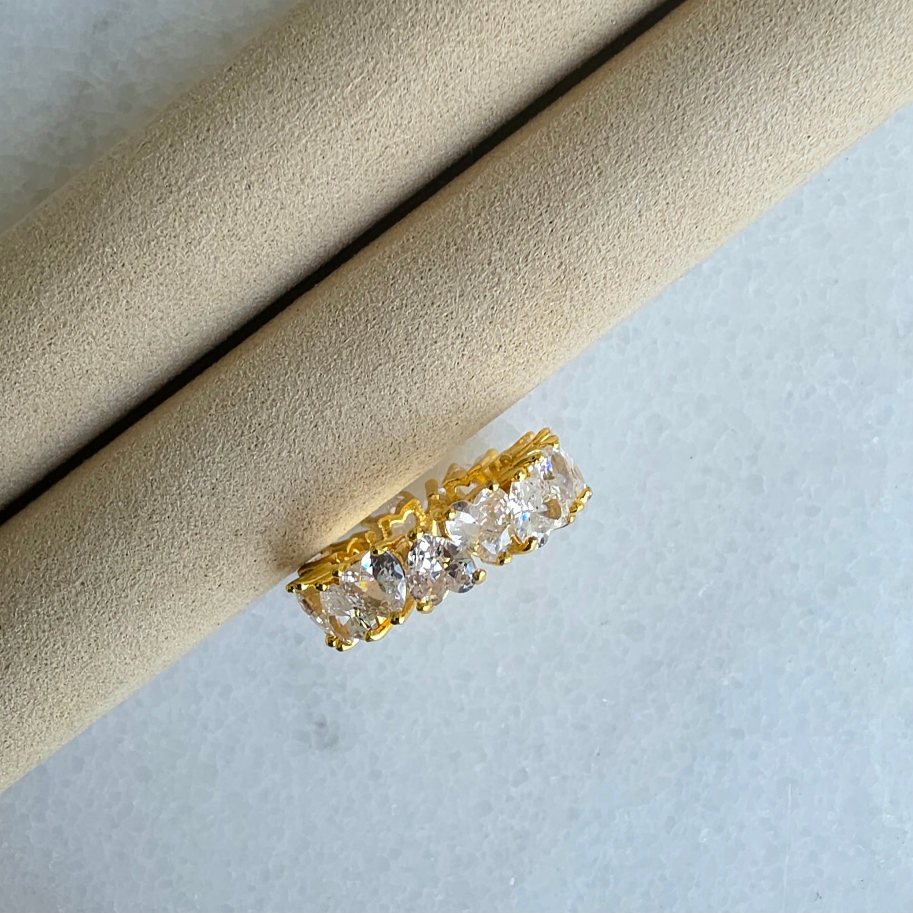 Gold ring with diamonds on a beige cushion against a light background