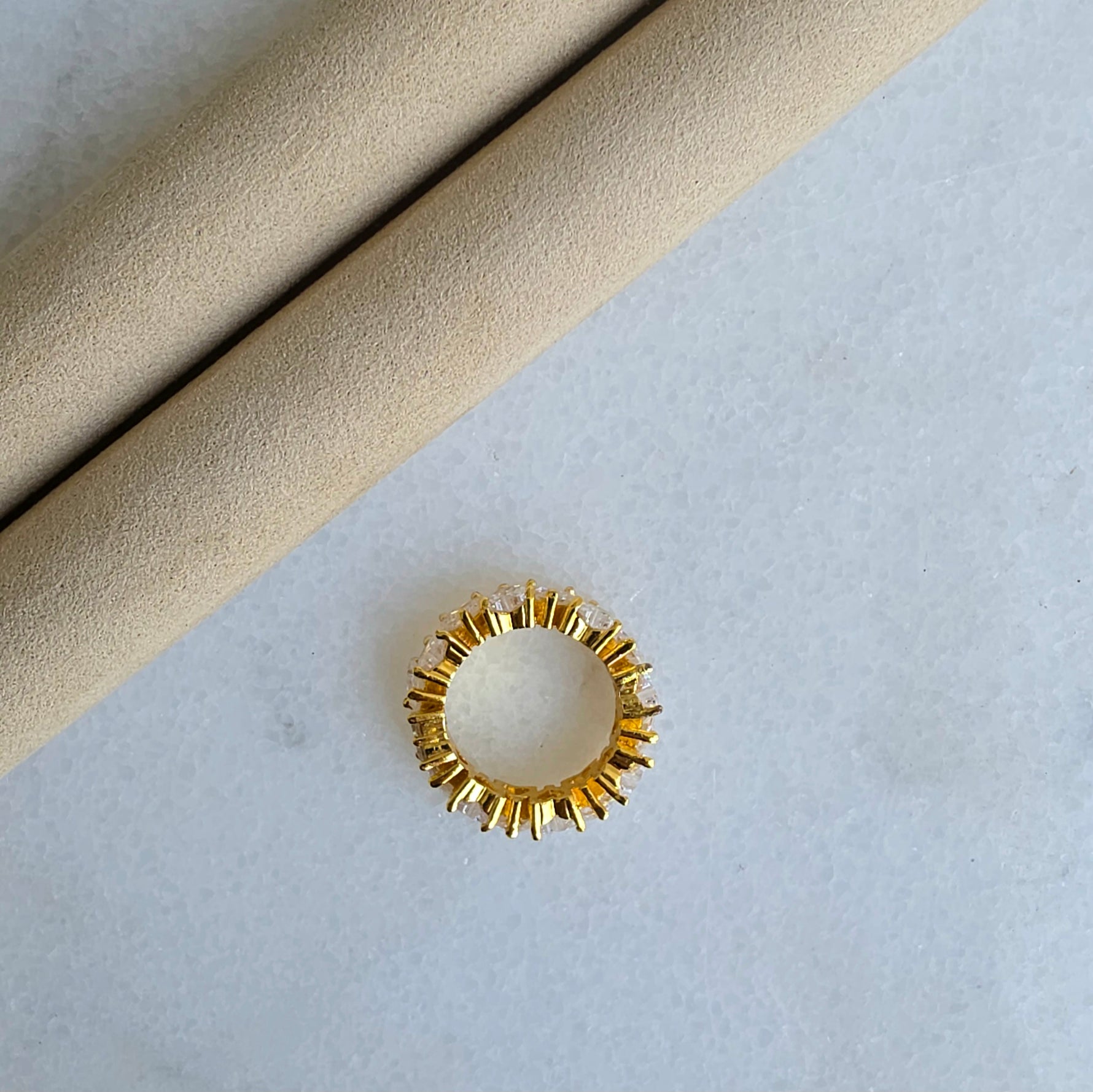 Gold ring with textured design on a light gray background