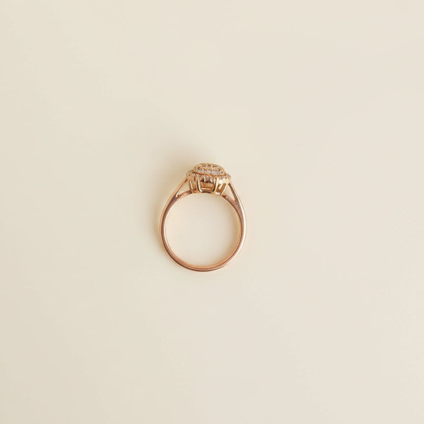 Gold ring with a diamond-like center on a light gray surface
