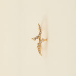 Gold necklace with diamond-like stones on a beige cushion against a light gray background