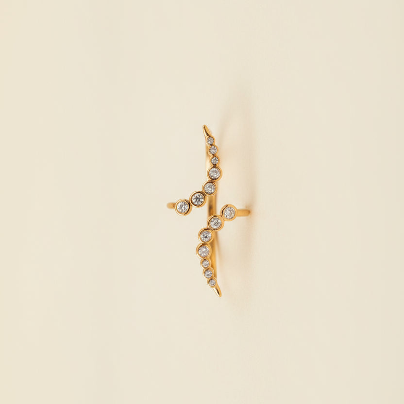 Gold necklace with diamond-like stones on a beige cushion against a light gray background