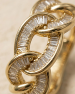 Gold ring with diamond accents on a beige background