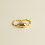 Gold ring with a unique design on a light gray background