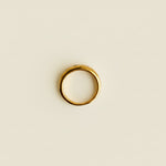 Gold ring on a light gray surface with a beige textured object