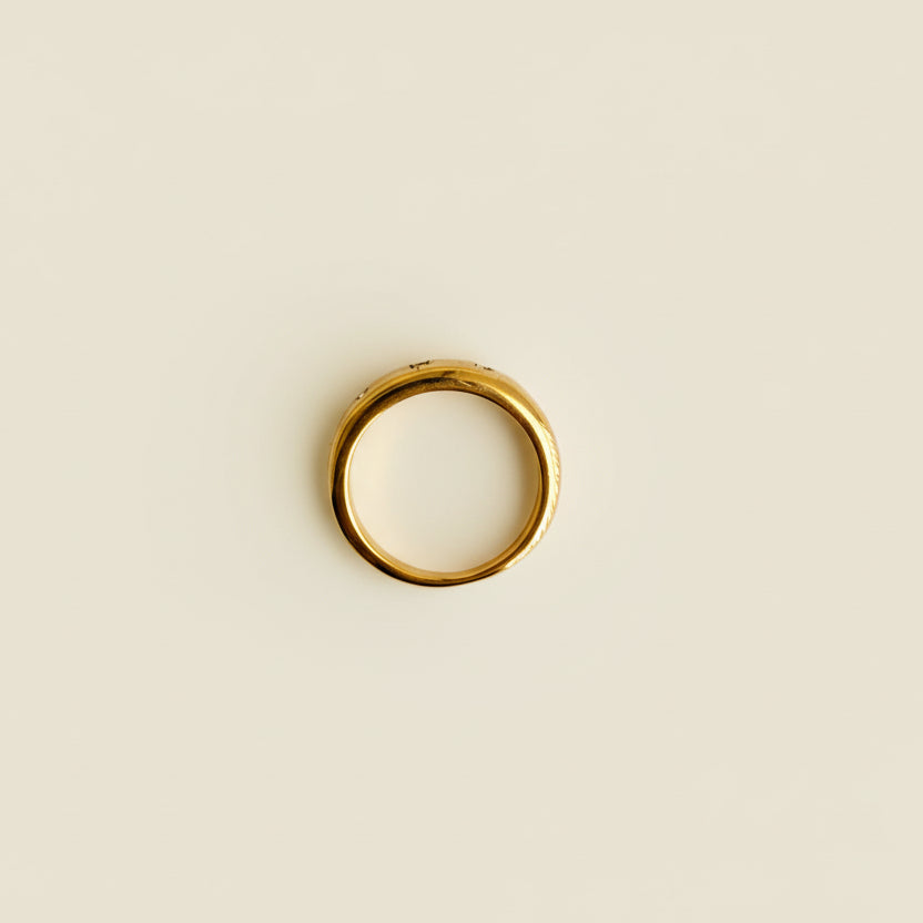 Gold ring on a light gray surface with a beige textured object