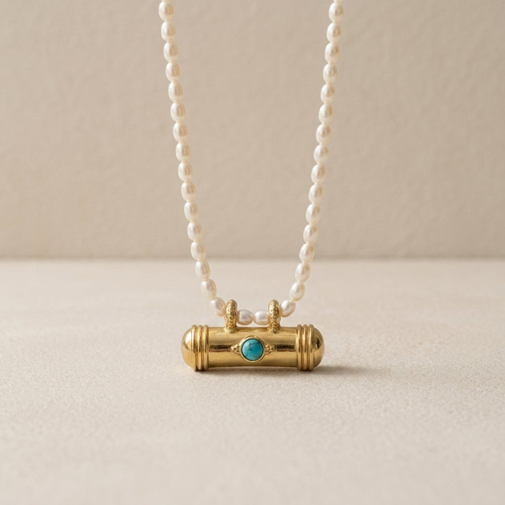 Pearl necklace with a gold and turquoise pendant on a beige background