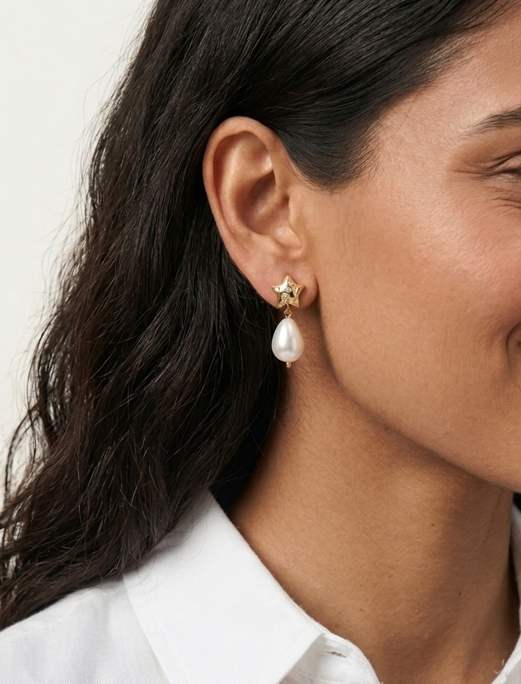 Woman wearing a pearl earring with a white shirt on a neutral background