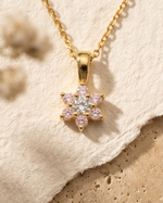 Gold necklace with a star-shaped pendant on a textured beige surface