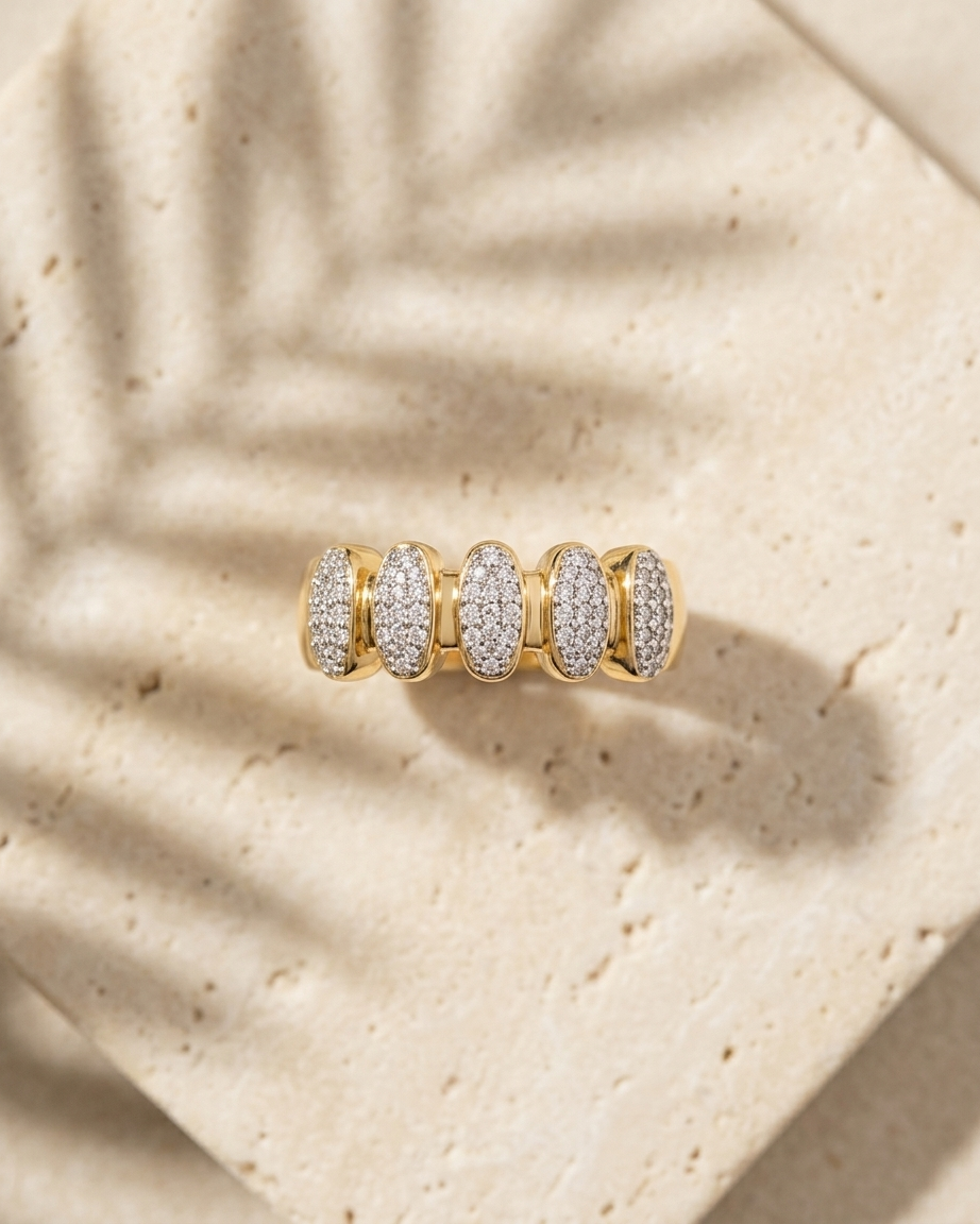Gold ring with embedded diamonds on a beige textured surface