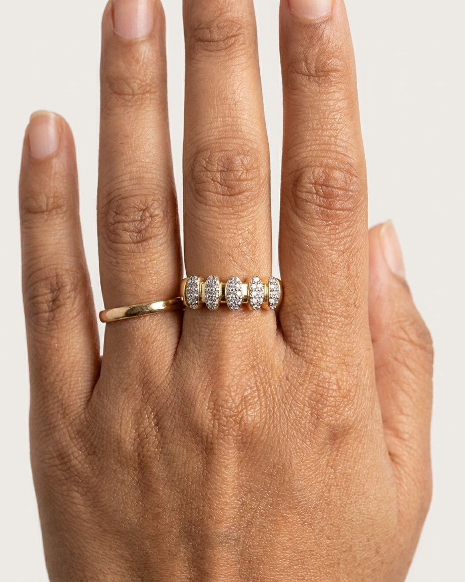 Hand wearing two gold rings with diamond accents on a neutral background
