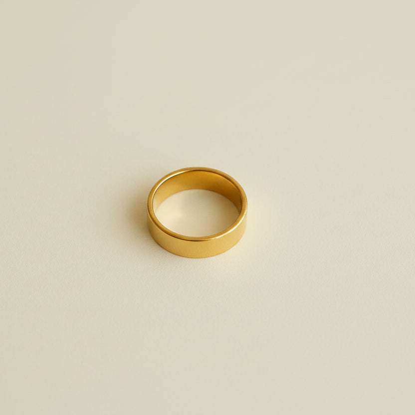 Gold ring on a light gray surface with a beige border