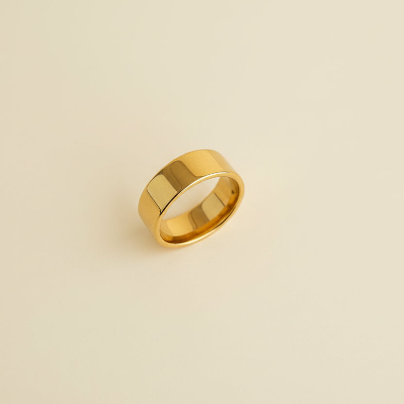 Gold ring on a textured beige surface