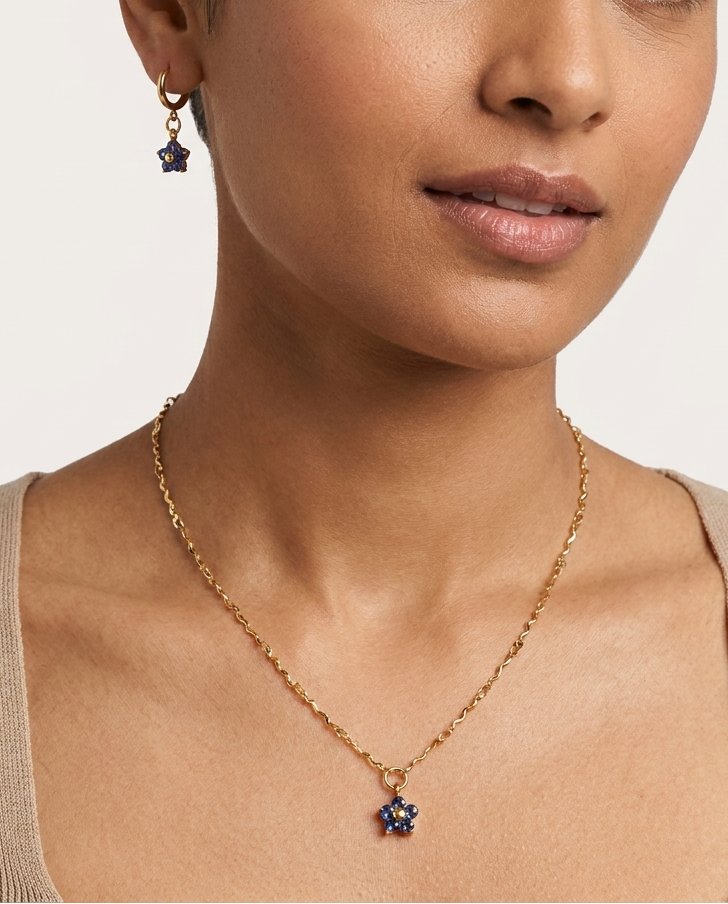 Woman wearing a gold necklace with a star pendant on a plain background