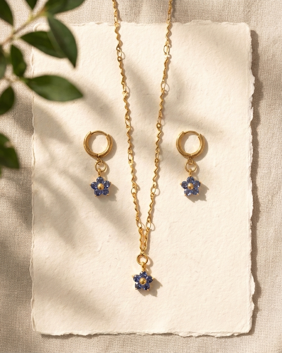 Gold necklace with blue flower pendants on a white card with a natural background