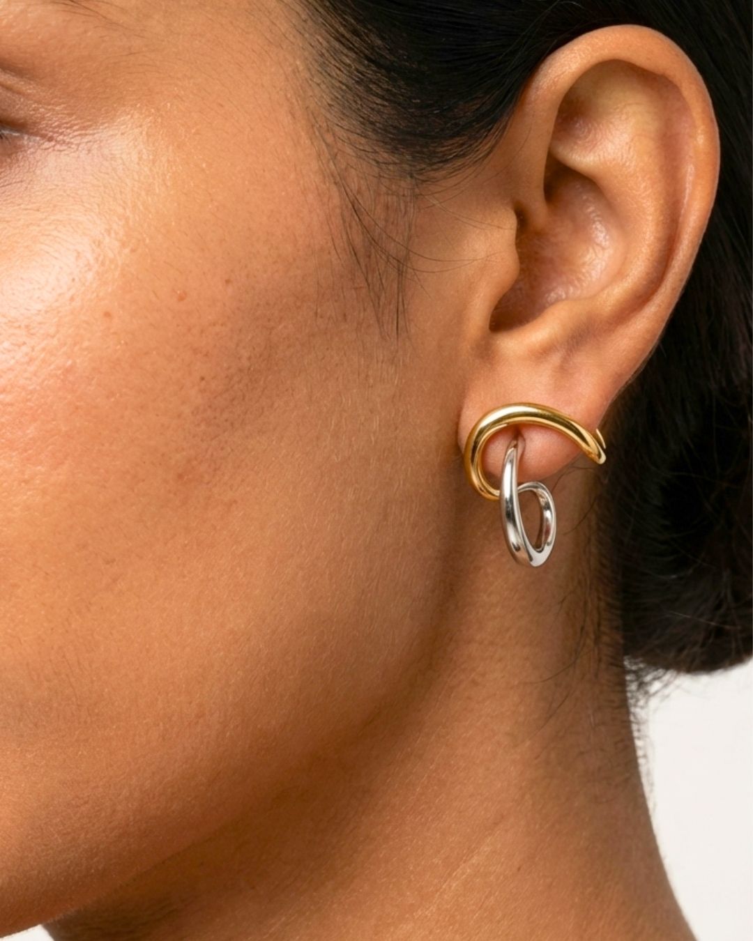 Close-up of an ear wearing a gold hoop earring 