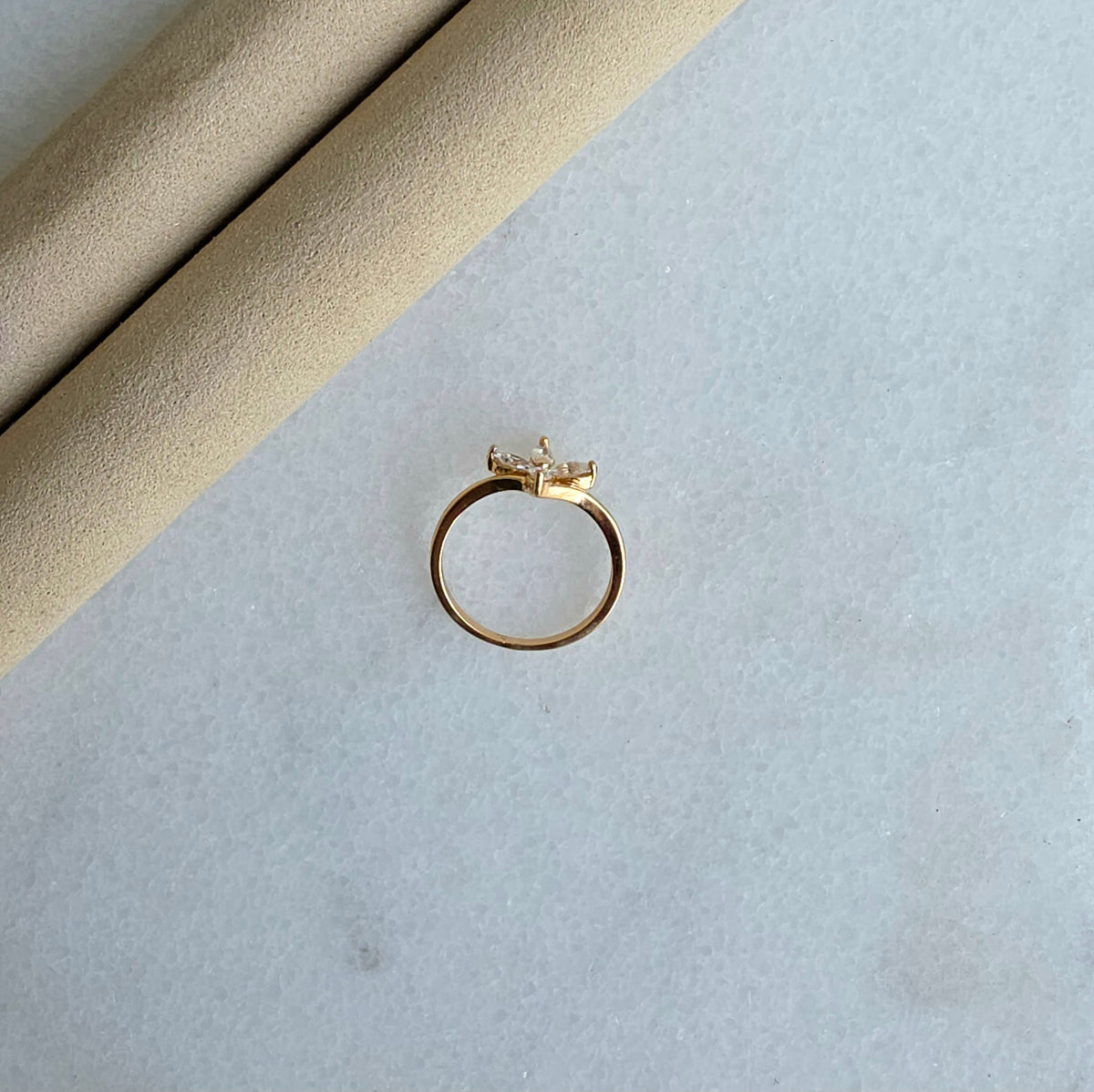 Gold ring with a diamond on a light gray surface