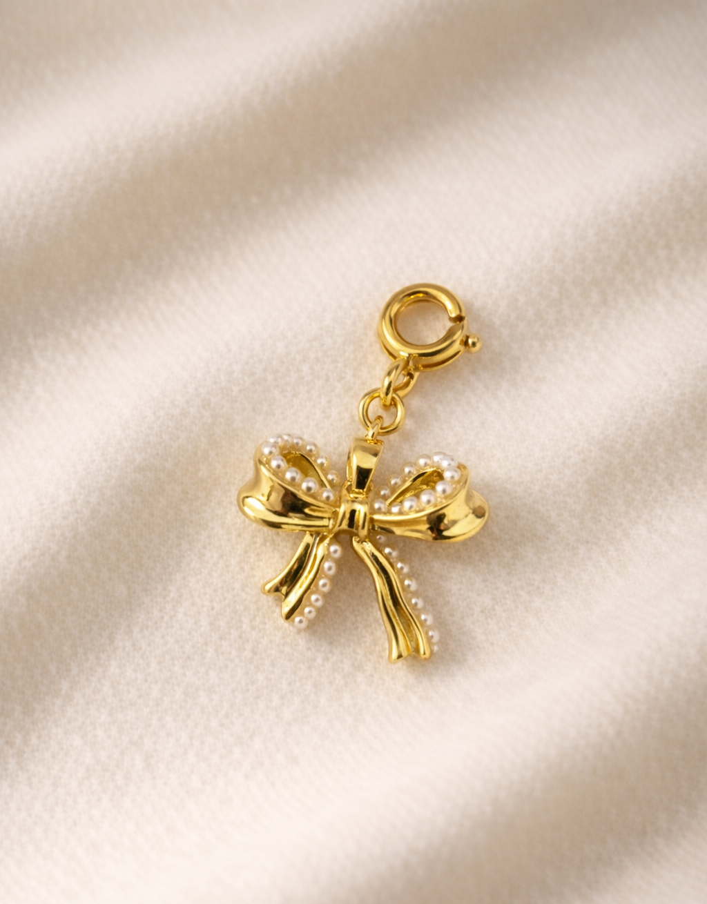 Gold bow-shaped charm on a beige fabric background