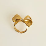 Gold bow-shaped earring on a light gray background