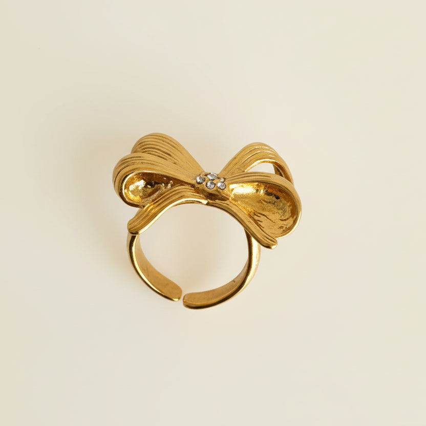 Gold bow-shaped earring on a light gray background