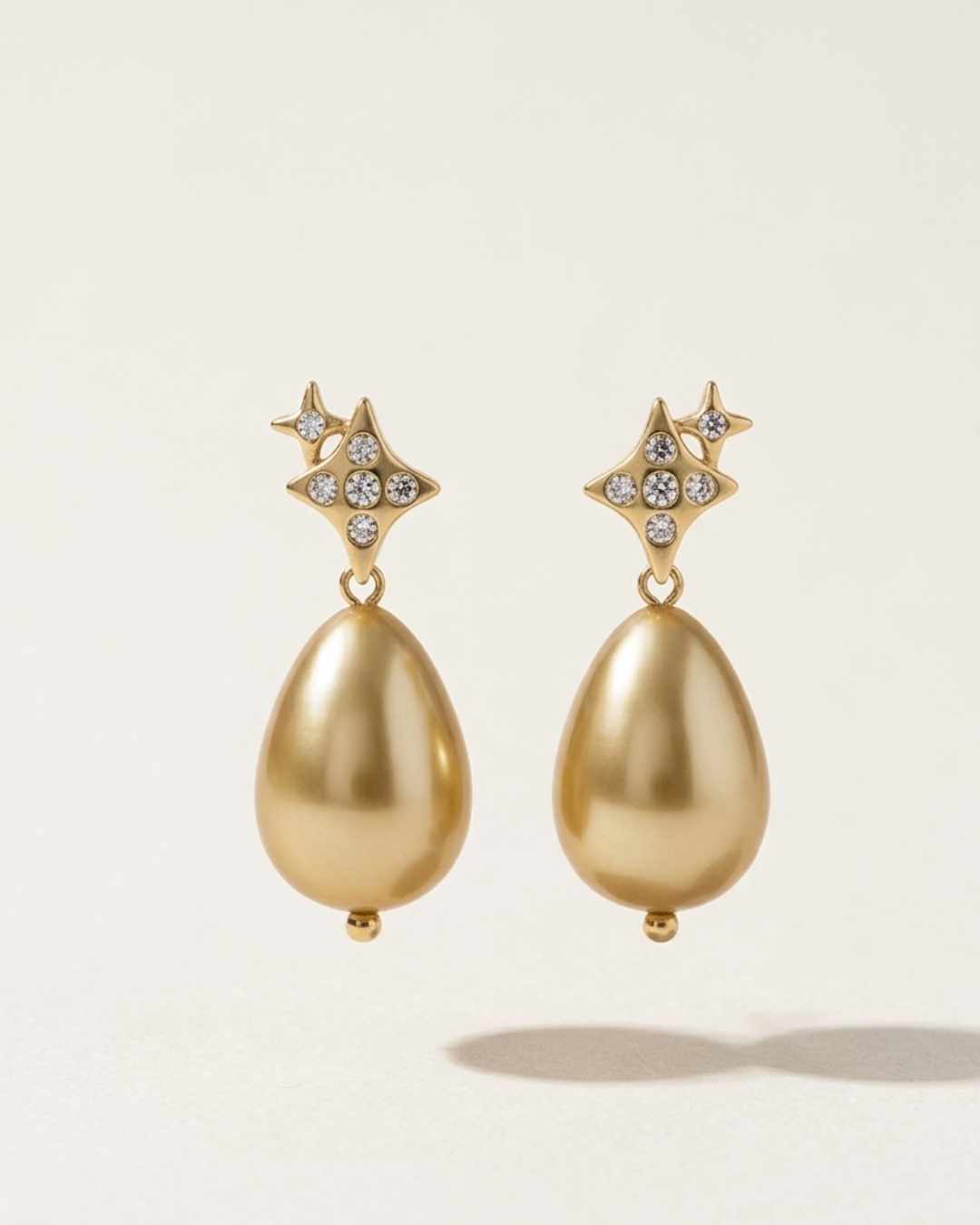 Gold earrings with star-shaped tops on a light background