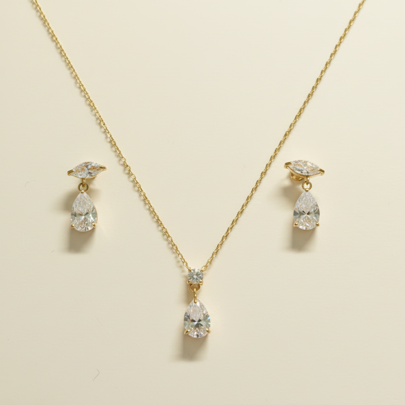 Gold necklace with diamond pendant and matching earrings on a white background