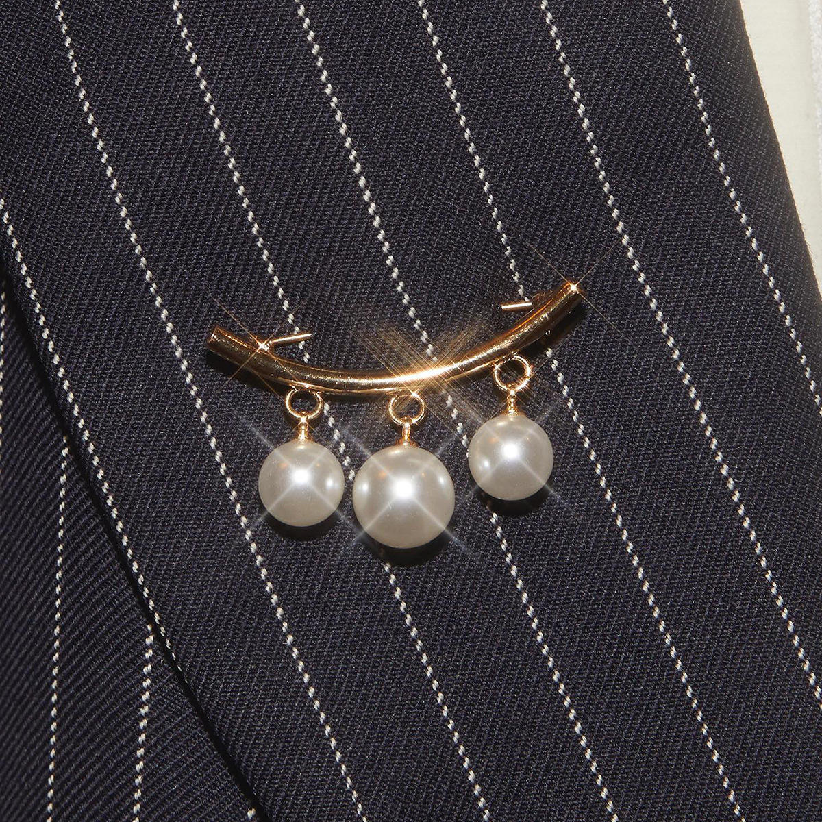 Pearl brooch on a black pinstripe suit jacket