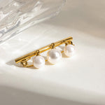 Gold brooch with three pearls on a light background