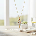 Necklace with tennis racket pendant on a table with a blurred background