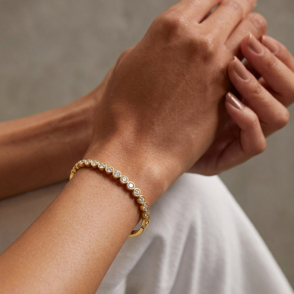 Gold bracelet with clear stones on a wrist against a neutral background