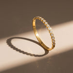 Gold bracelet with embedded diamonds on a beige background