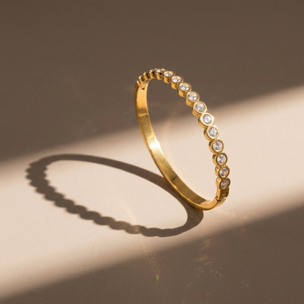 Gold bracelet with embedded diamonds on a beige background