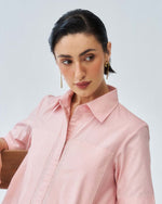 Woman wearing a light pink shirt against a plain background