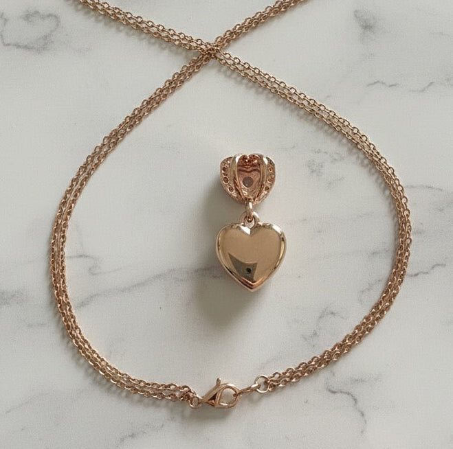 Rose gold heart-shaped pendant necklace on a marble surface