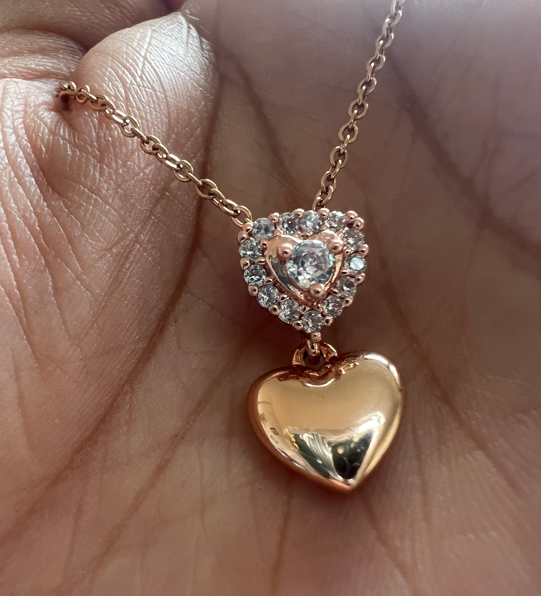 Gold necklace with heart-shaped pendant on a hand