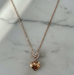 Rose gold necklace with heart-shaped pendant on a marble surface