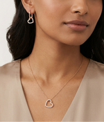 Woman wearing a heart-shaped earring and necklace on a neutral background
