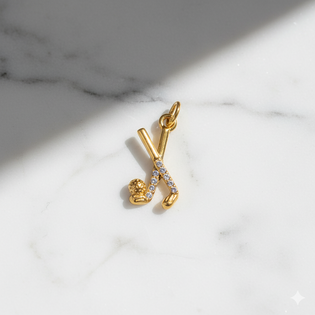 Gold pendant with hockey sticks on a marble surface