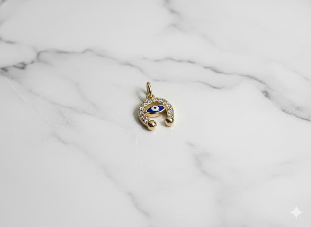 Gold pendant with a blue eye design on a marble surface