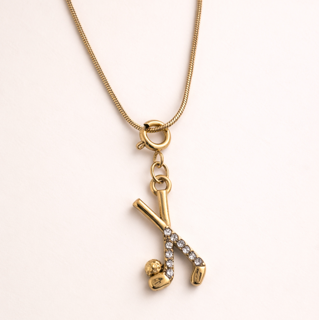 Gold necklace with a pendant on a light pink background