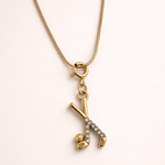 Gold necklace with a pendant on a light pink background