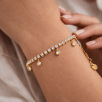 Gold bracelet with diamond accents on a wrist against a neutral background