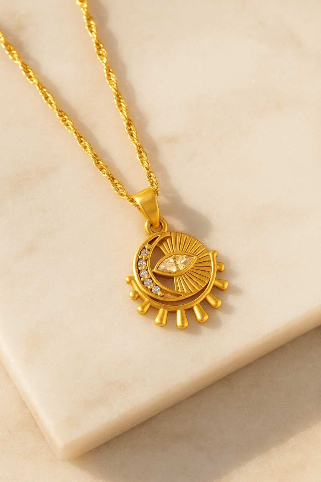 Gold necklace with a circular pendant featuring an eye design on a beige surface