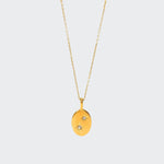 A gold-colored necklace with a charm featuring two starry stones on a white background.