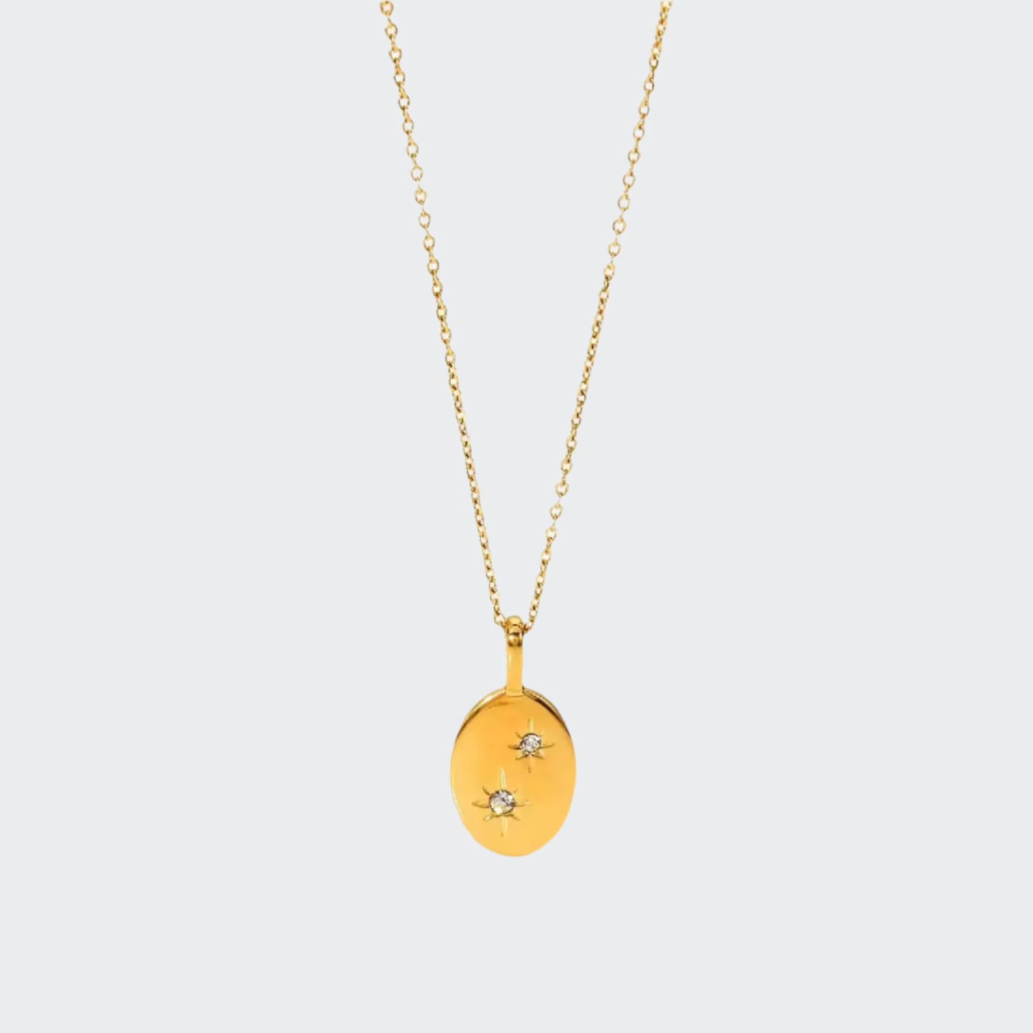 A gold-colored necklace with a charm featuring two starry stones on a white background.