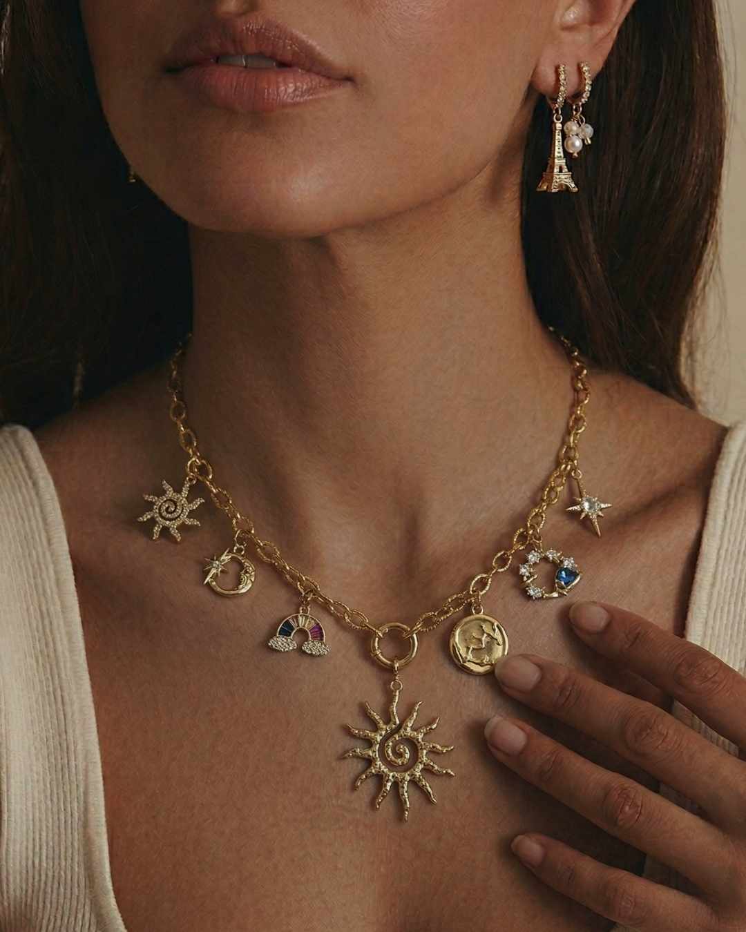 Close-up of a woman wearing a gold necklace with various charms.