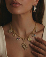 Close-up of a woman wearing a gold necklace with various charms.
