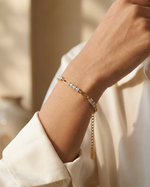 Gold bracelet with clear stones on a wrist against a neutral background