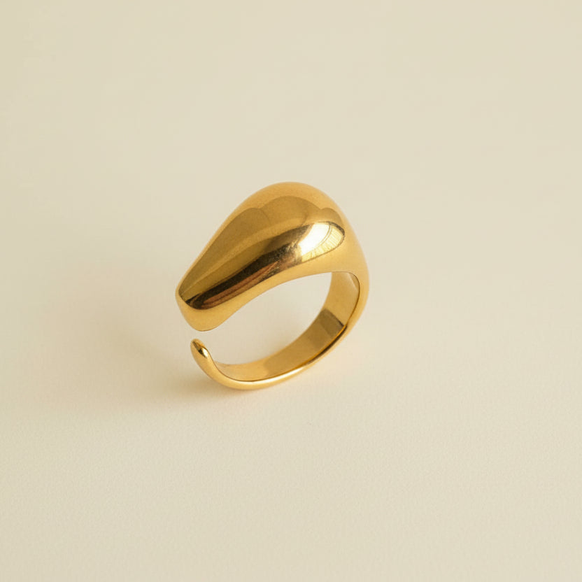 Gold ring on a beige cylindrical object with a light gray background